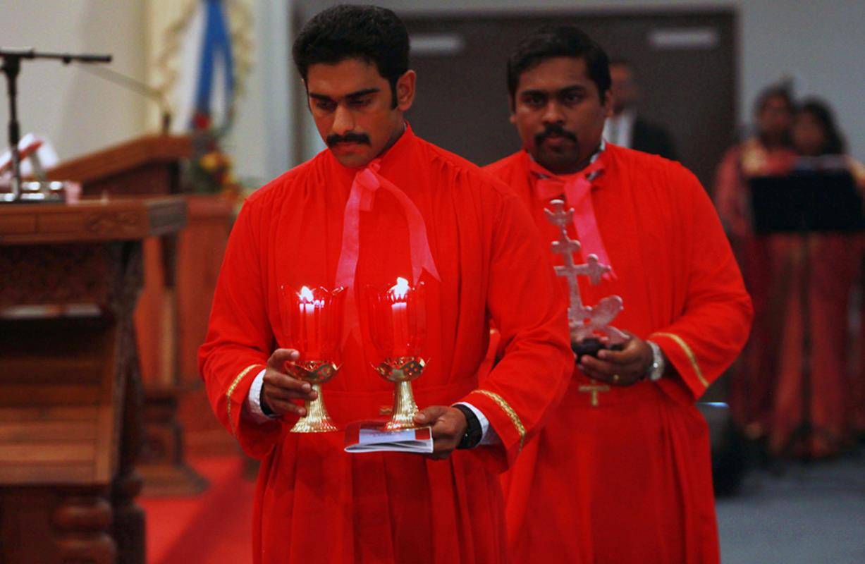 Two candles, symbolizing the Old and New Testaments, and a St. Thomas Cross are taken to be placed on the small altar in the sanctuary.