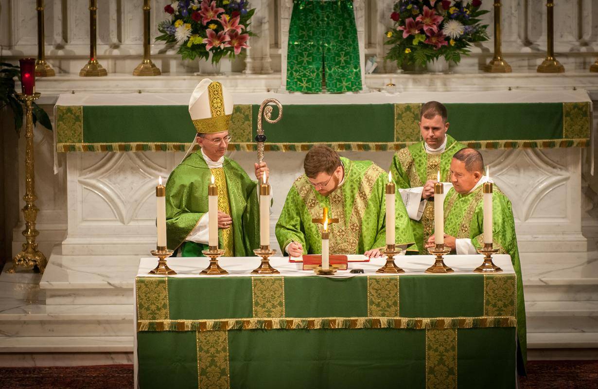 Father Paul Buchanan signs the official documents naming him pastor of Our Lady of Grace Church in Greensboro (Photos by Jarek Lucek)