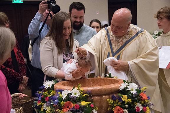 Monsignor Anthony Marcaccio, pastor, baptizes a baby at the Easter Vigil Mass March 31 (Photo provided by MaryAnn Luedtke Photography)