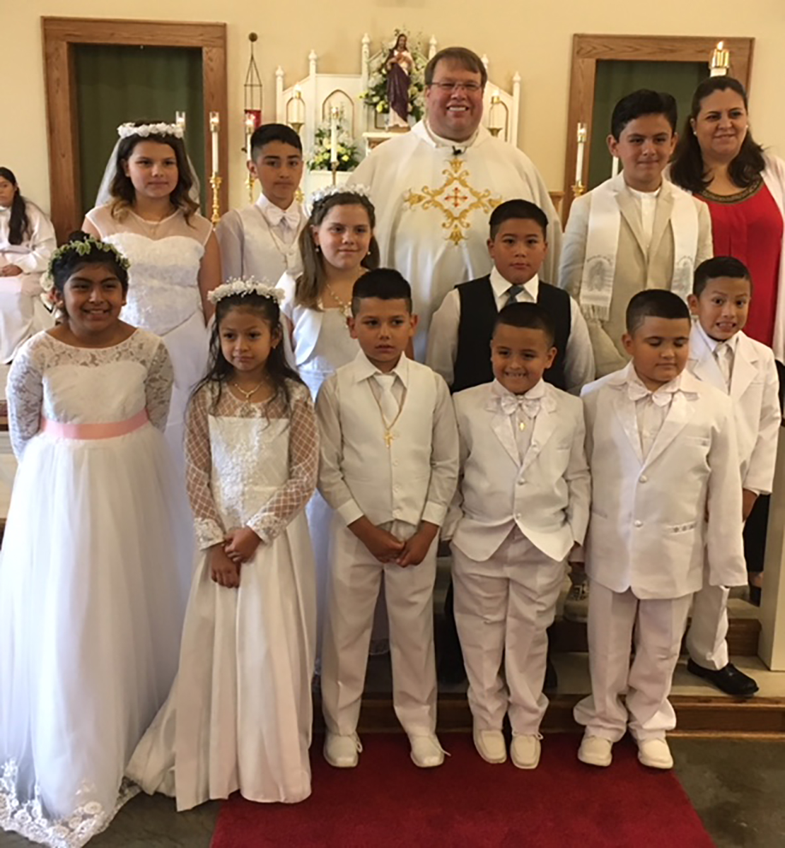 JEFFERSON — Thirteen children from St. Francis of Assisi Church received their first Holy Communion on the Feast of Corpus Christi. Eleven of the children are pictured with their pastor, Father James Stuhrenberg and Celia Cabrera. (Patrick Hession | Catho