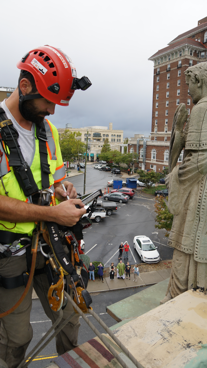 Watched by parishioners and passersby below, Mike Russell with Vertical Access prepares to rappel down the side of St. Lawrence Basilica.