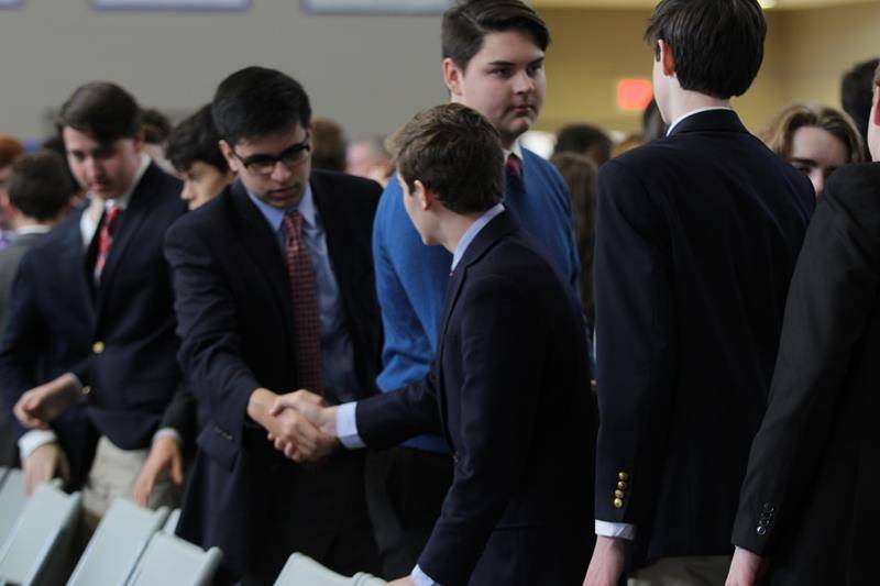 Students share a sign of peace during Mass Dec. 6.