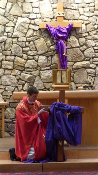 Father Matthew Codd holds the cross during a cross veneration service at St. Elizabeth Church on Good Friday. Amber Mellon
