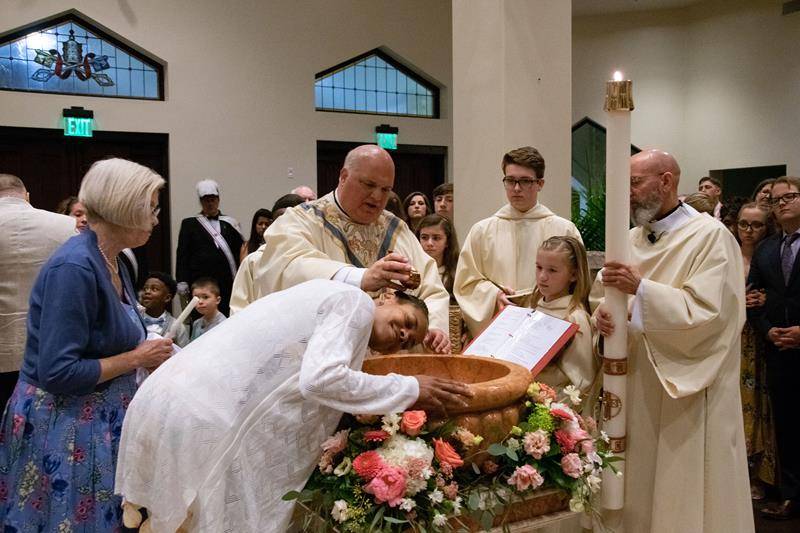 Monsignor Anthony Marcaccio administers the sacrament of baptism during the Easter Vigil at St. Pius X Church in Greensboro. (Photo by Mary Ann Luedtke)