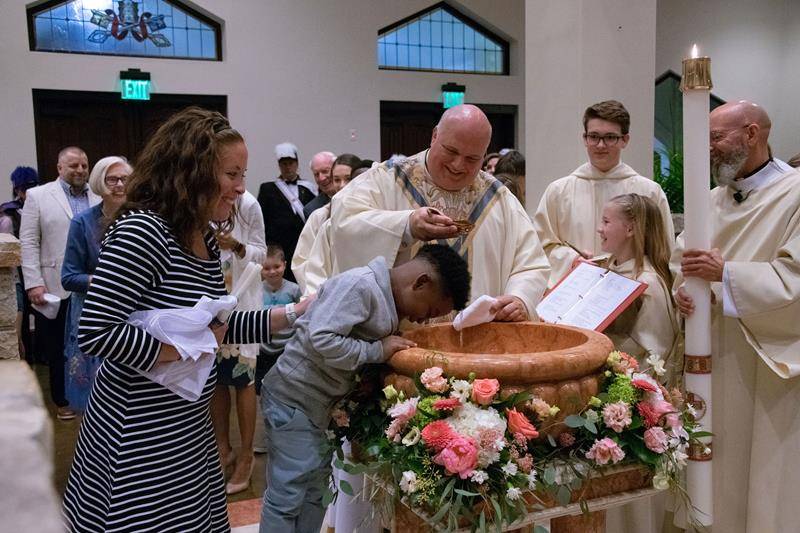 Monsignor Anthony Marcaccio, pastor, baptizes a catechumen during the Easter Vigil at St. Pius X Church in Greensboro April 20. (Photo by Mary Ann Luedtke)