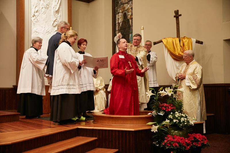 Jesuit Father James Shea administers the sacrament of baptism during the Easter Vigil at St. Peter Church in Charlotte April 20.  (Photo by Bea Staub)