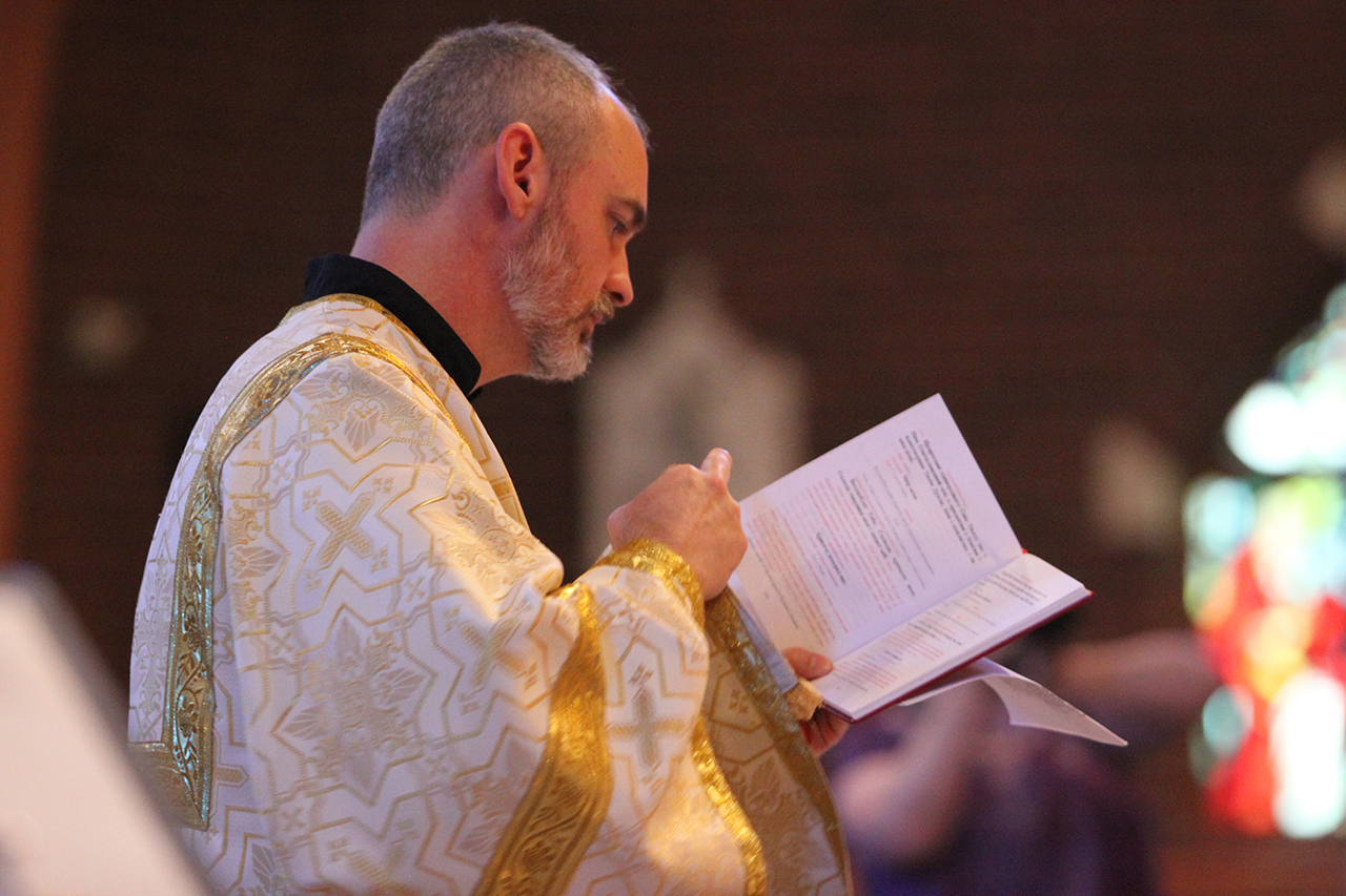 Deacon Matthew Hanes of St. Basil Church chants during the Divine Liturgy, holding his orarion.
