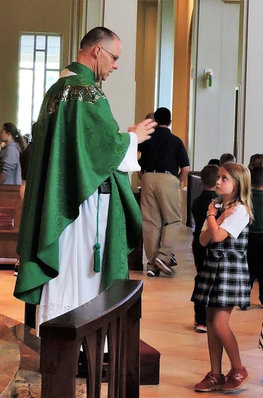 1st grader Lily Reimels receives a blessing from Father John.