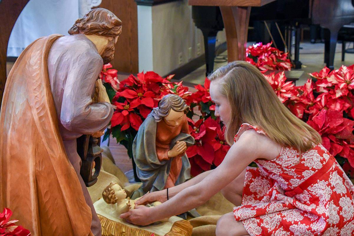 HAYESVILLE — A young member of Immaculate Heart of Mary Mission places the baby Jesus in the Nativity display near the altar during the vigil Mass for Christmas. (Phil Roche | Catholic News Herald)
