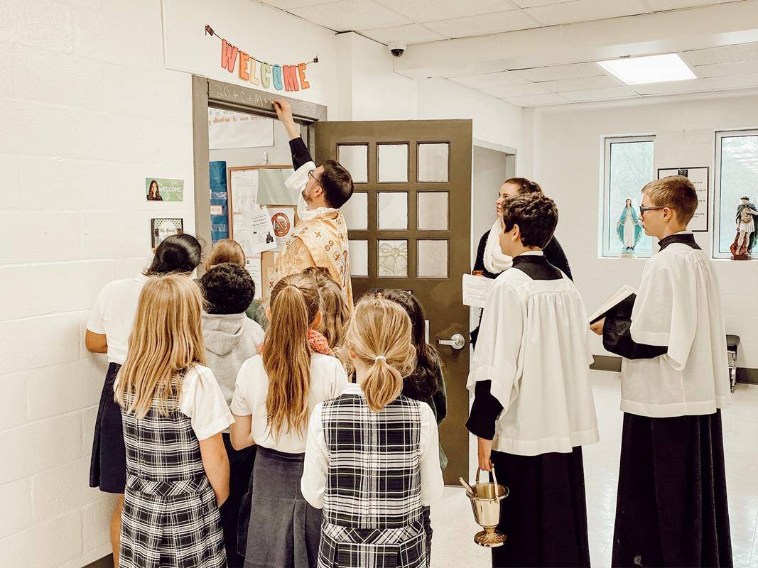 Father Lucas Rossi, pastor, blesses a classroom at St. Michael School in Gastonia for the Feast of the Epiphany. (Photo provided by St. Michael School)