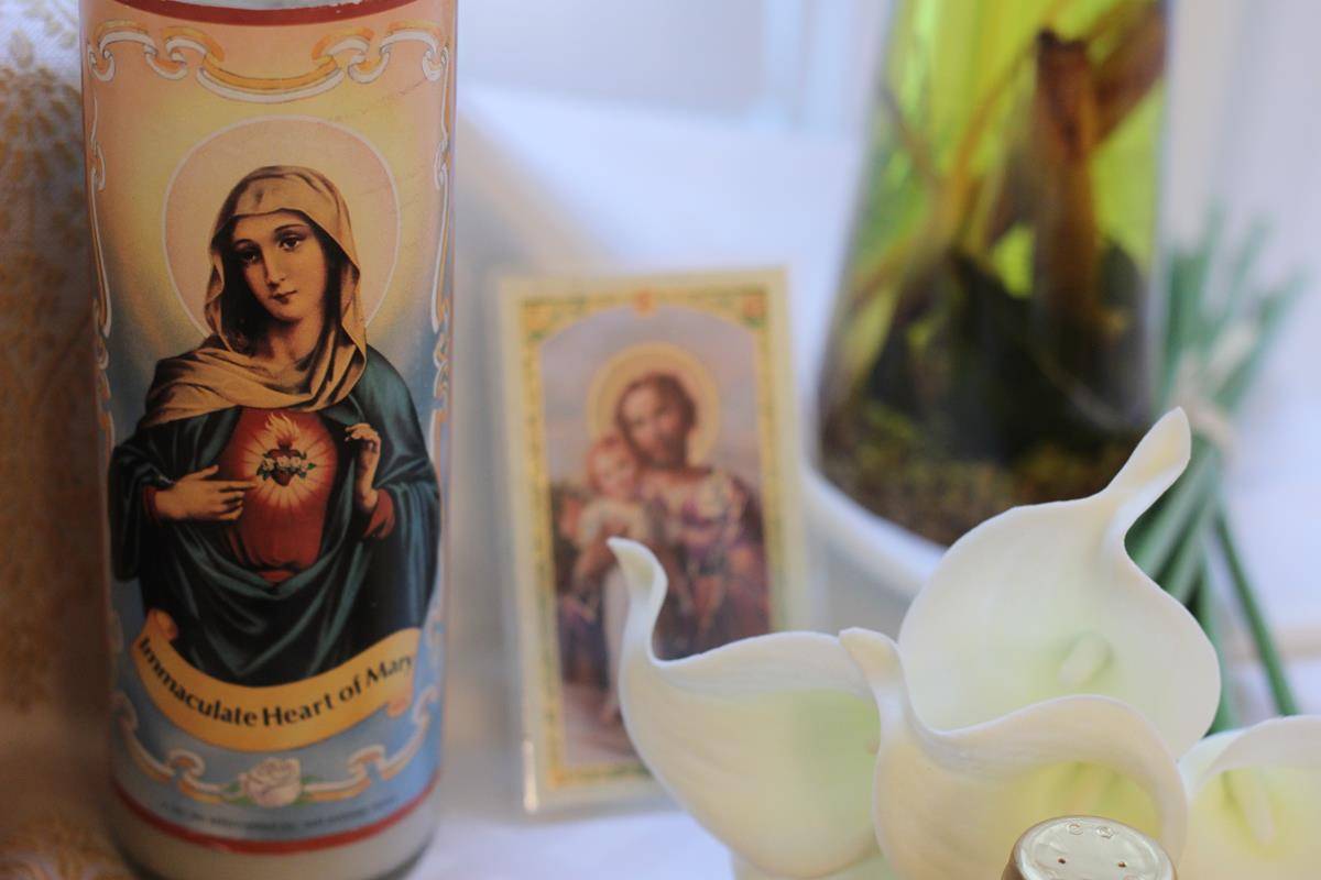 Holy card with candle on table.