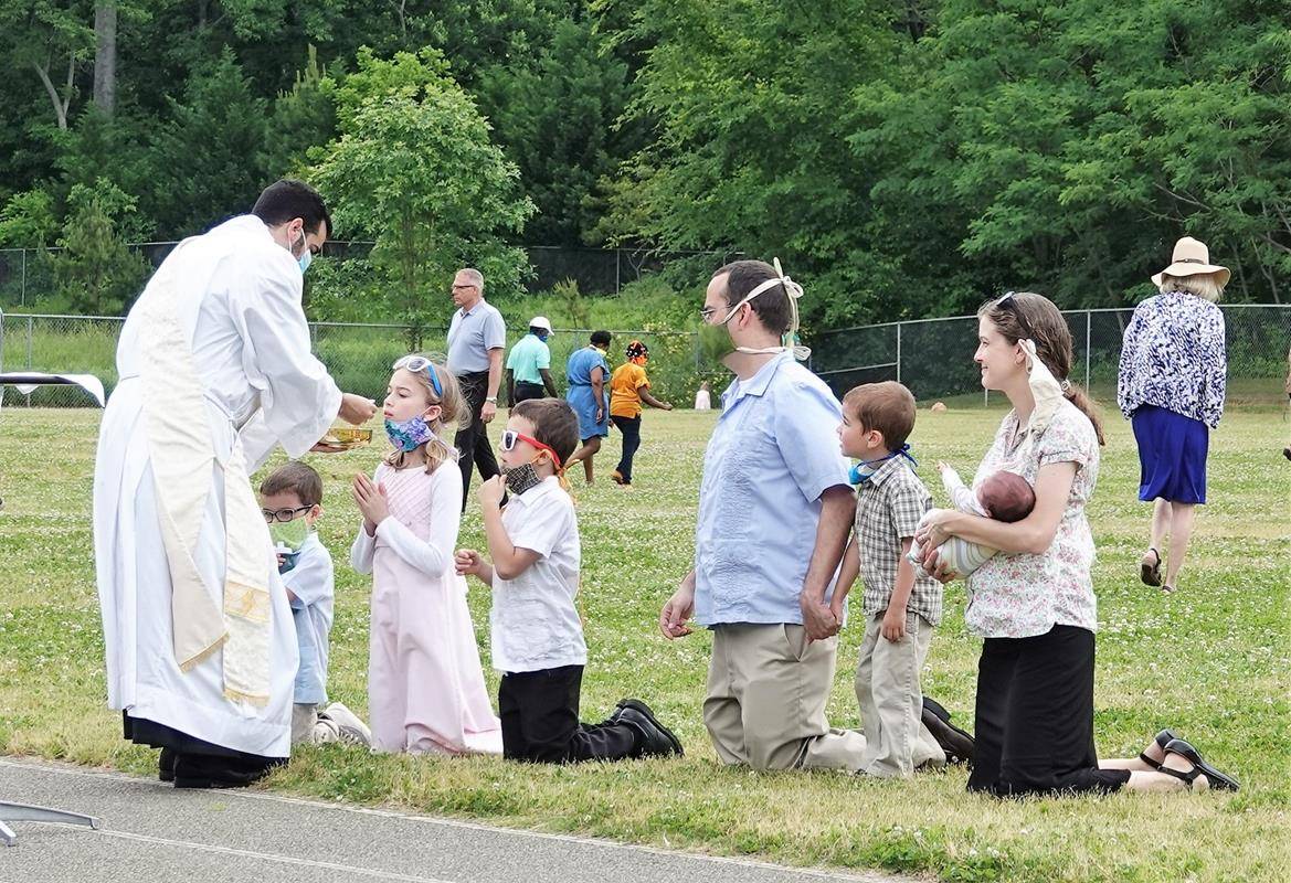Transitional Deacon Jonathan Torres distributes Holy Communion at an outdoor Mass at St. Mark Church in Huntersville May 17. (Photo provided by Amy Burger)