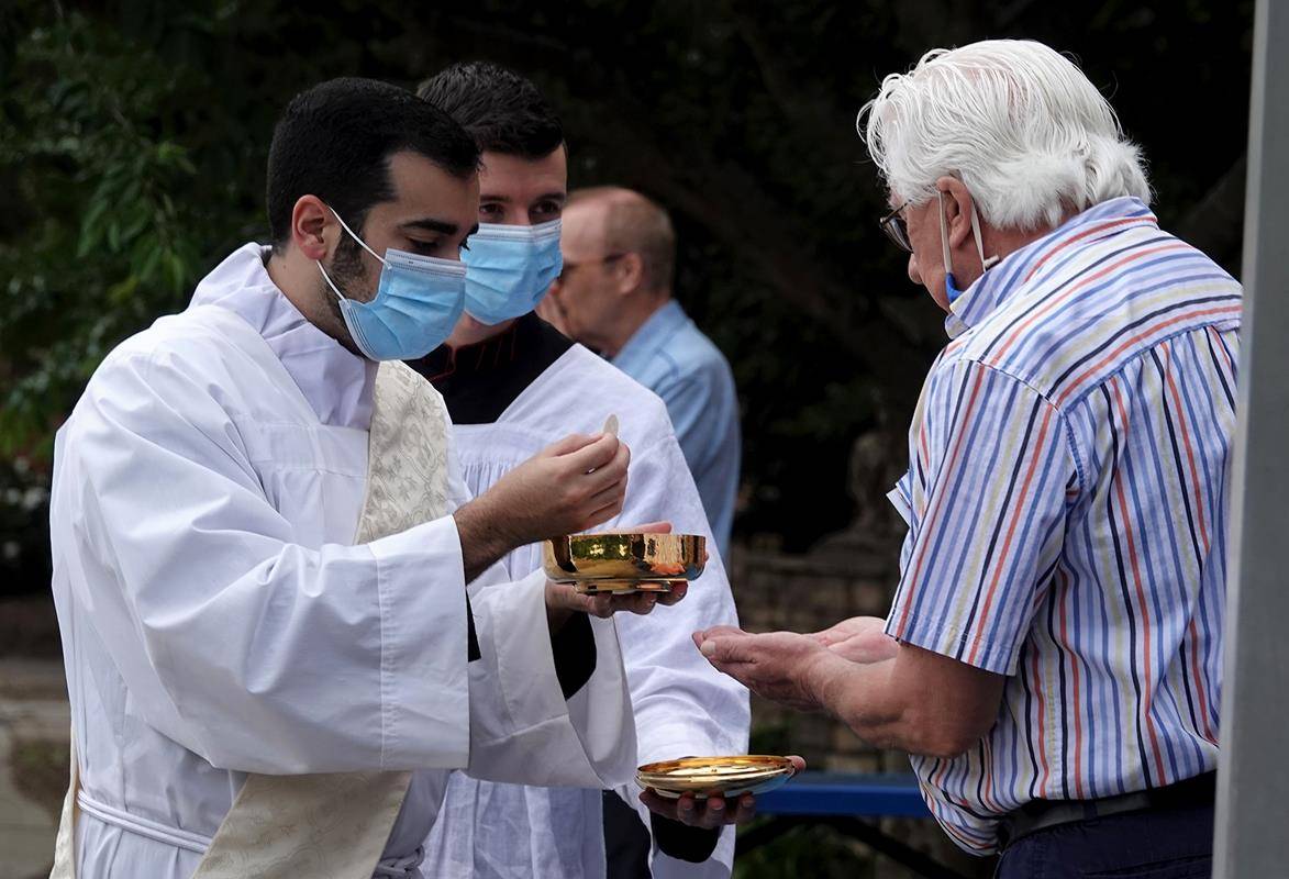 Transitional Deacon Jonathan Torres distributes Holy Communion at an outdoor Mass at St. Mark Church in Huntersville May 17. (Photo provided by Amy Burger)
