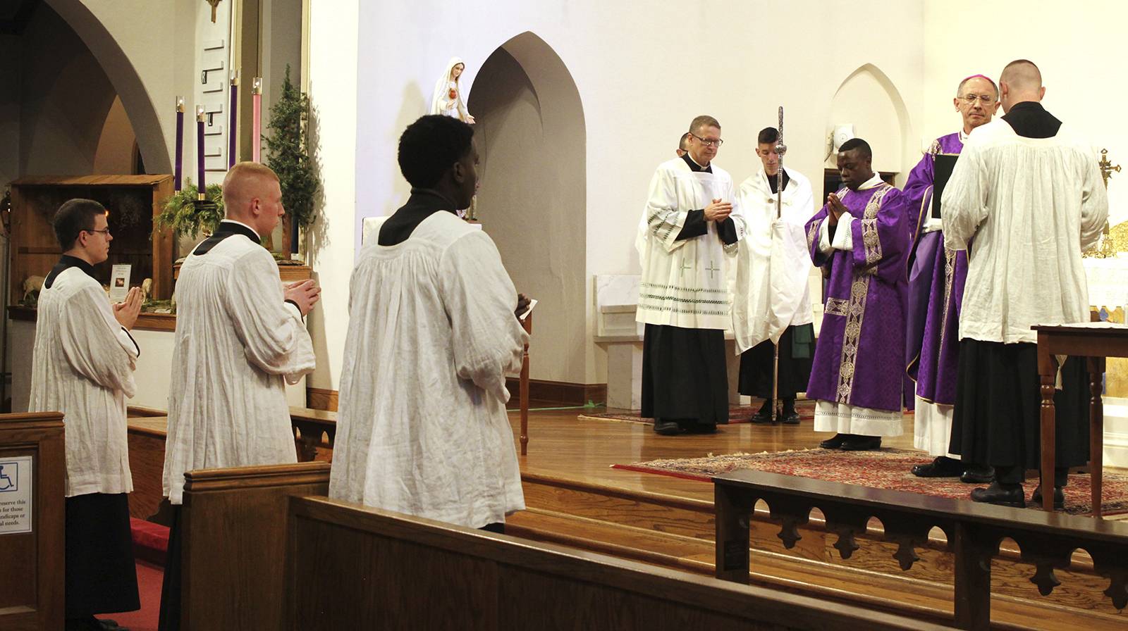 Diocese of Charlotte seminarians (from left) Christopher Brock, Peter Rusciolelli and Chinonso Nnebe-Agumadu stand before Bishop Peter Jugis before being instituted as lectors.
