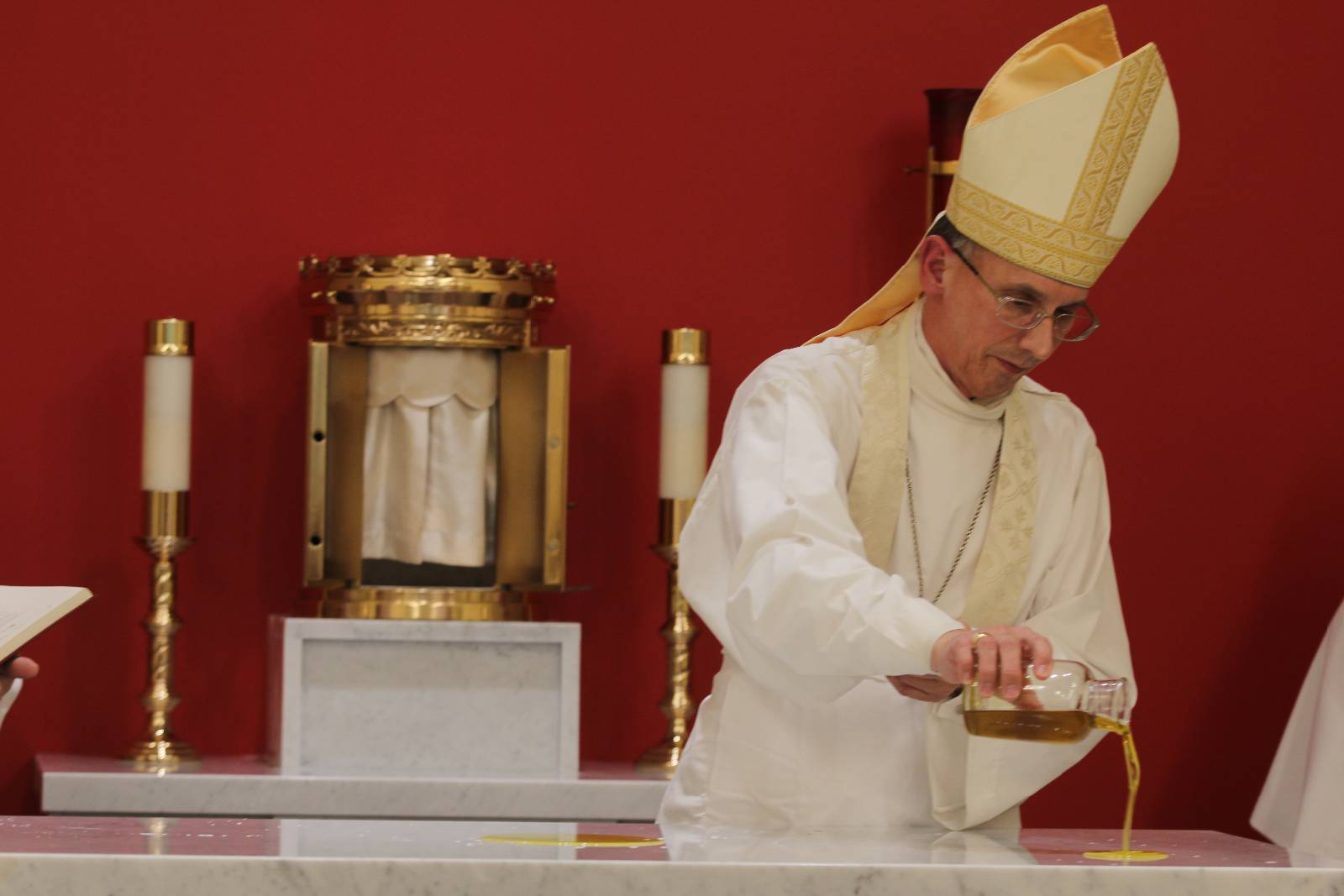 During the dedication rite for the new altar in the Holy Family Chapel in Clemmons, Bishop Peter Jugis pours sacred oil over the top of the new marble altar.