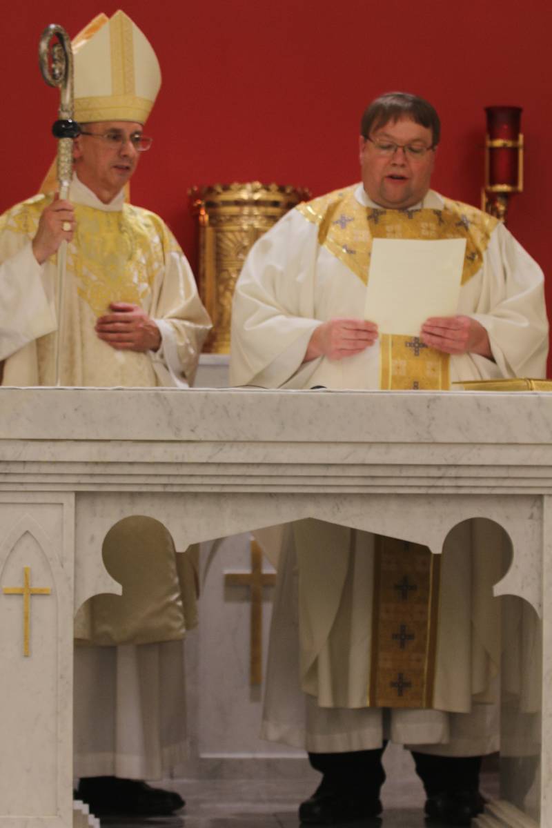 During the official pastor installation, Father James Stuhrenberg reads aloud the oath as Bishop Jugis looks on during the ceremony held Jan. 27 after the dedication of the new chapel at Holy Family Church in Clemmons.