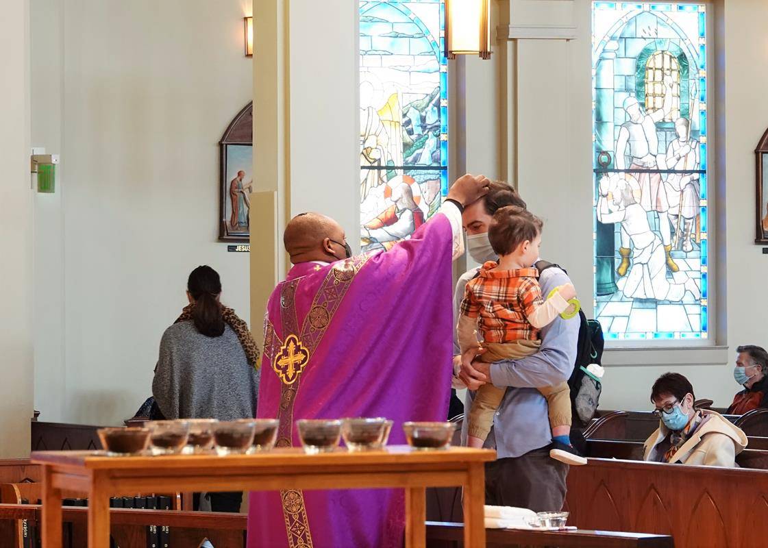 HUNTERSVILLE — Father Melchesideck Yumo distributes ashes to Colin Riggles and his son Carter at St. Mark Church in Huntersville.  (Photos provided by Amy Burger.)  