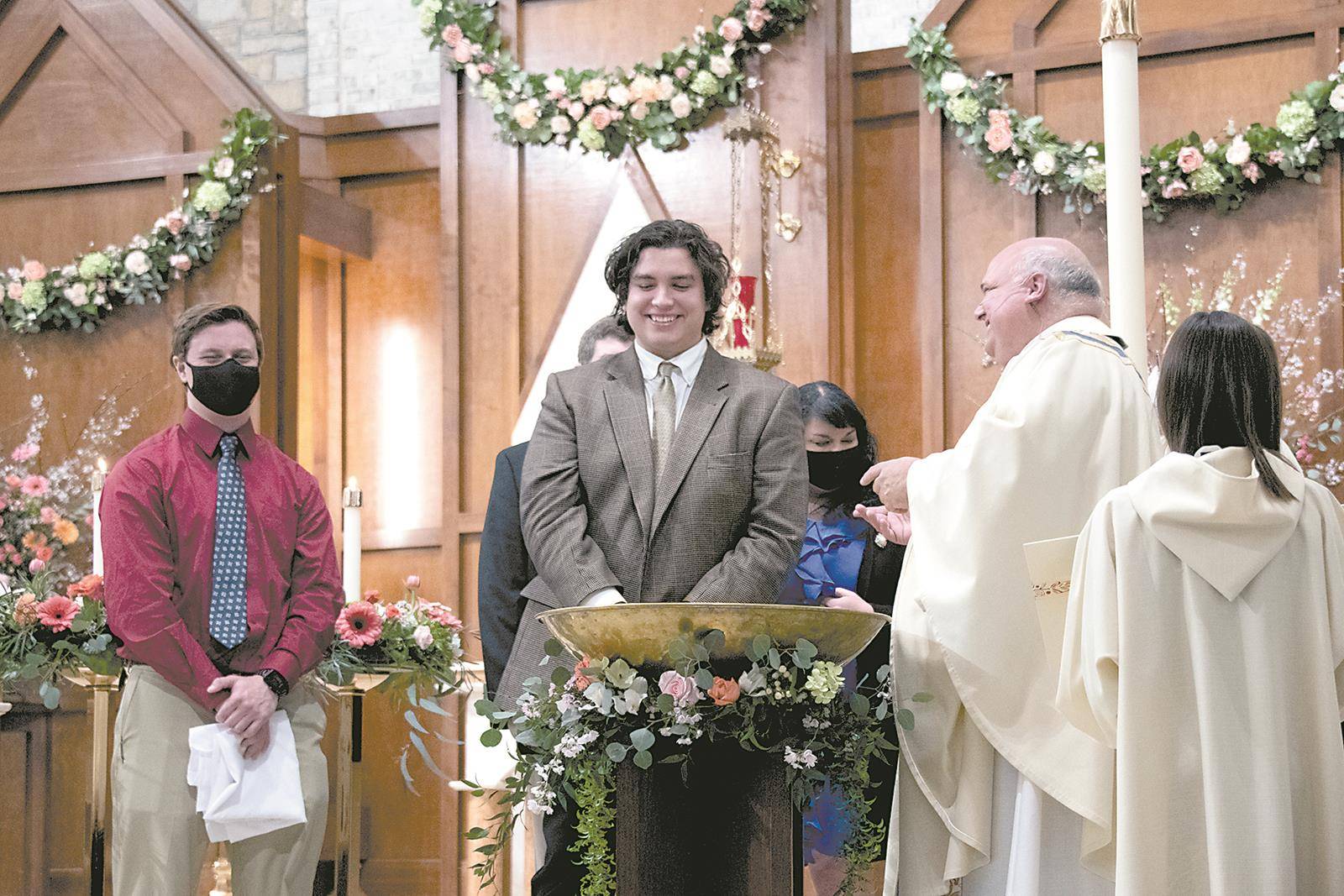 Monsignor Anthony Marcaccio, pastor, welcomes Jacob Gates into the Catholic Church, administering the sacrament of baptism and other sacraments of initiation during the Easter Vigil April 3 at St. Pius X Church in Greensboro. (Photo by MaryAnn Luedtke)