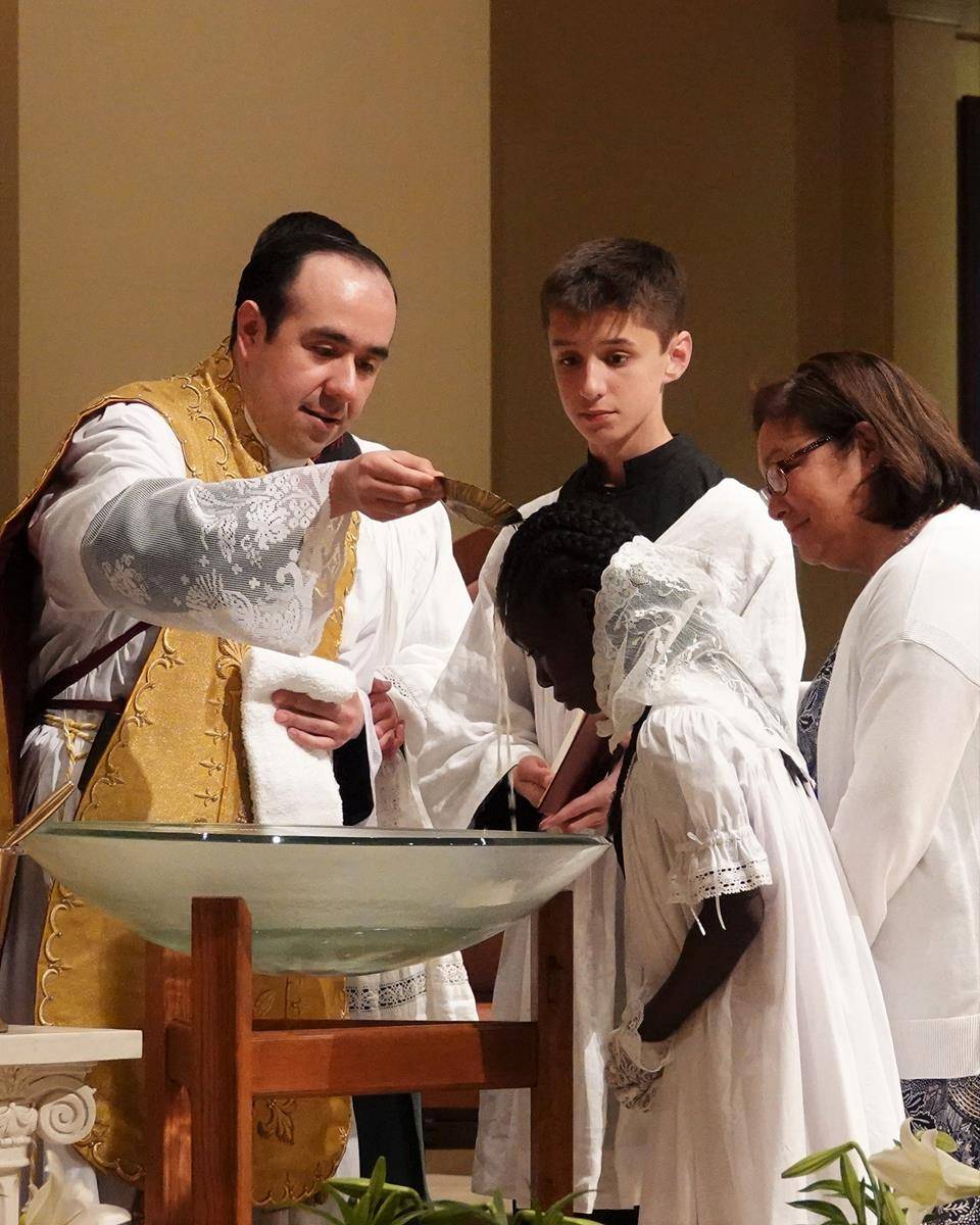 Father Alfonso Gámez, parochial vicar at St. Mark Church in Huntersville, baptizes Milan Howard during the Easter Vigil April 3. (Photo provided by Amy Burger)
