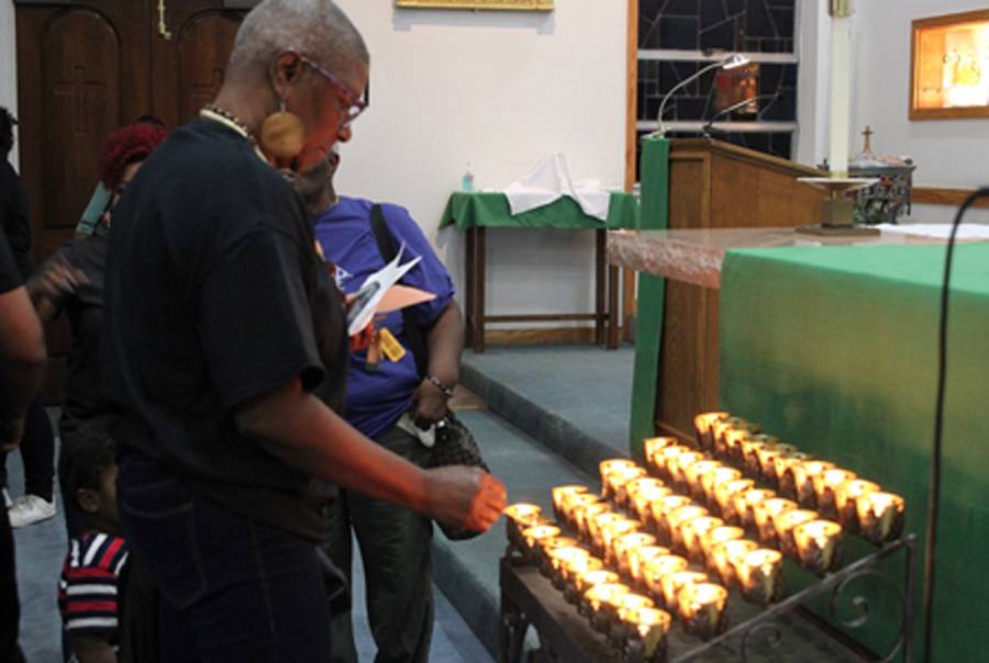 Justin Carr's aunt, Delores Carr, lights the final candle at the end of a special prayer service held at Our Lady of Consolation Church Sept. 23, one day after Carr died