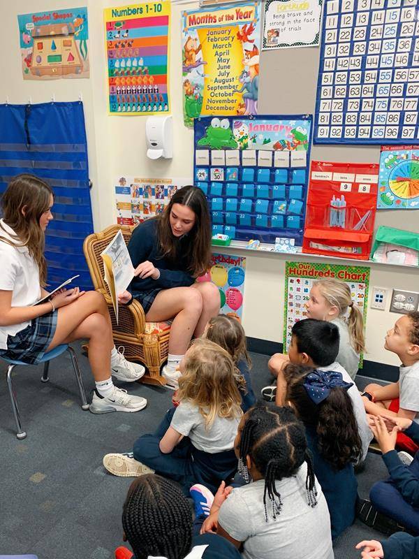 Bishop McGuinness freshmen Francesca Daccio and Lauren Showers read to young students at their alma mater, Immaculate Heart of Mary School in High Point.