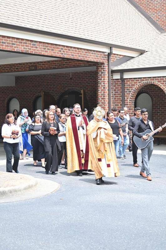 Fr. José Juya, parish vicar, lead the Eucharist Processional with Fr. Lucas Rossi, pastor at St. Michael Church in Gastonia. A crowd of parishioners follow them through the facilities until gather at Mass.