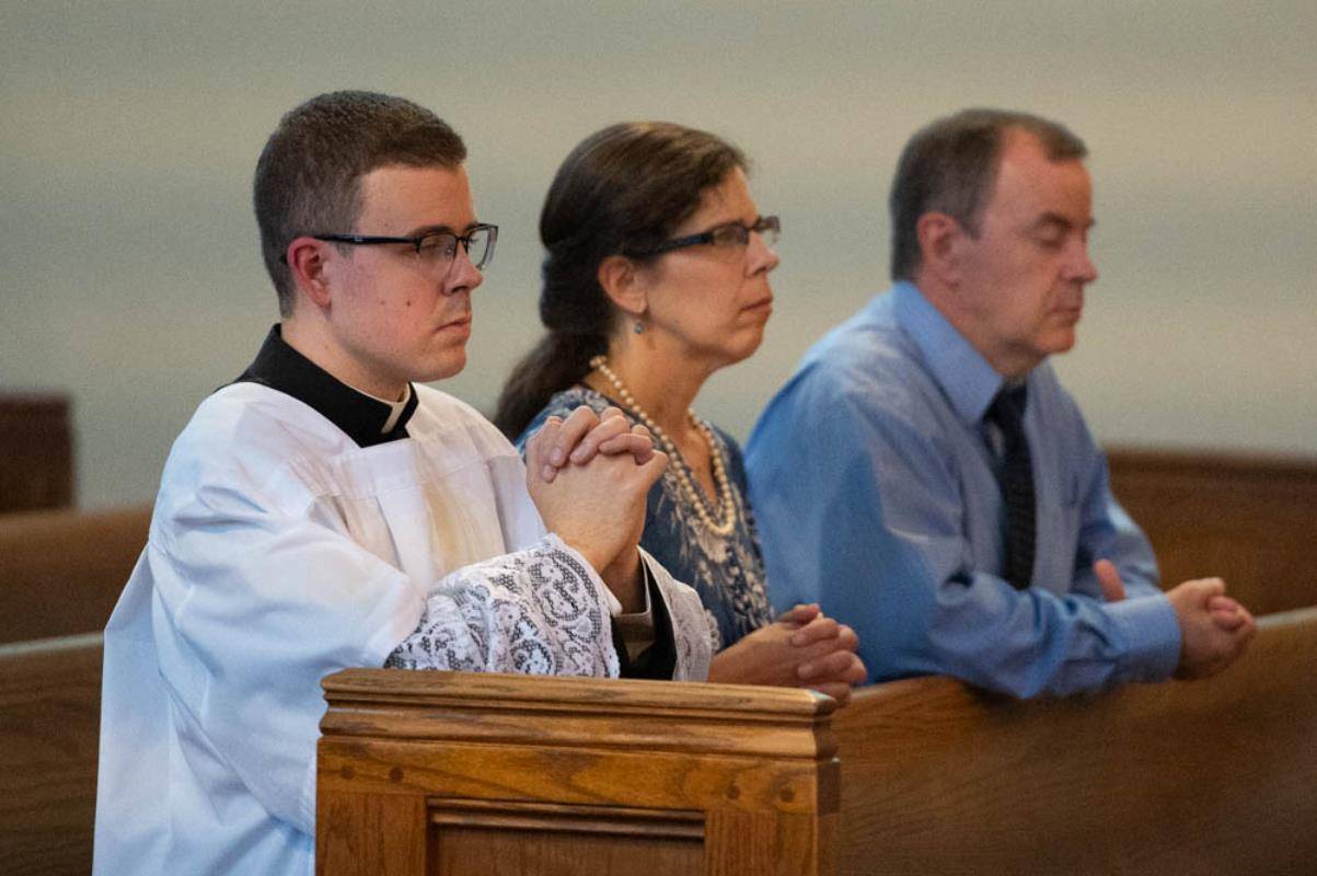 Christopher Brock and his parents, Steve and Susan Brock, pray during the Holy Hour at St. Patrick Cathedral Thursday.