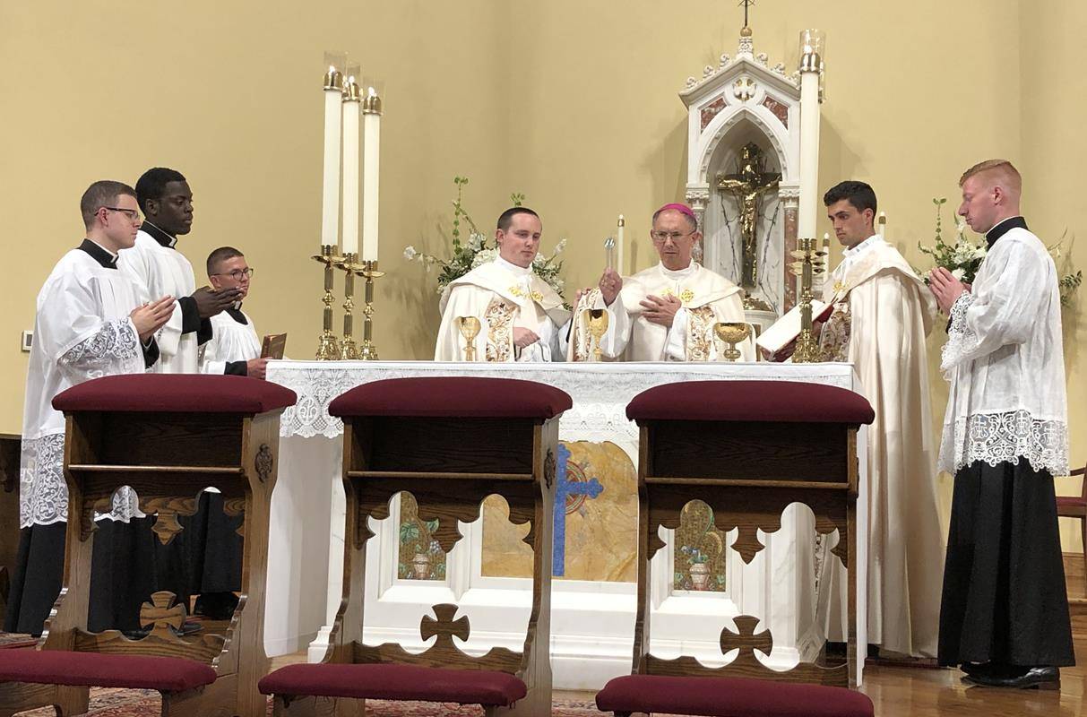 As they stand to the left and right side of the altar, Bishop Peter Jugis blesses the personal chalices for the three men being ordained this Saturday.