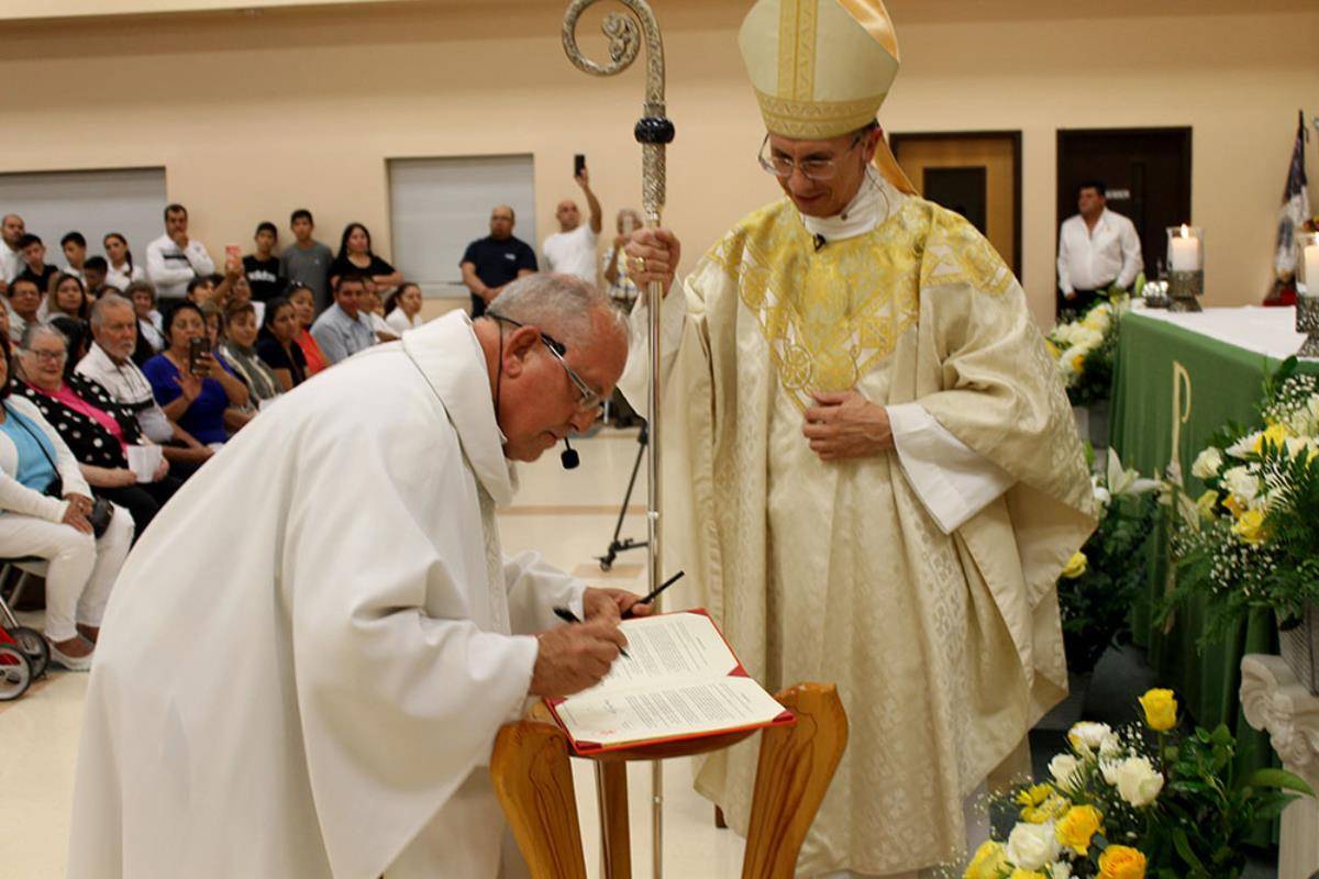 Father Gregory Gay signs the official Church documents in front of Bishop Peter Jugis during his installation as pastor of Our Lady of Guadalupe Parish in 2019