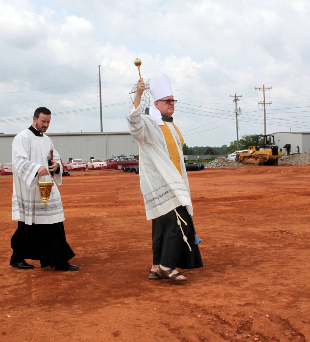 Bishop Martin, followed by Father Miguel Sanchez, blesses the site of the future church with holy water.