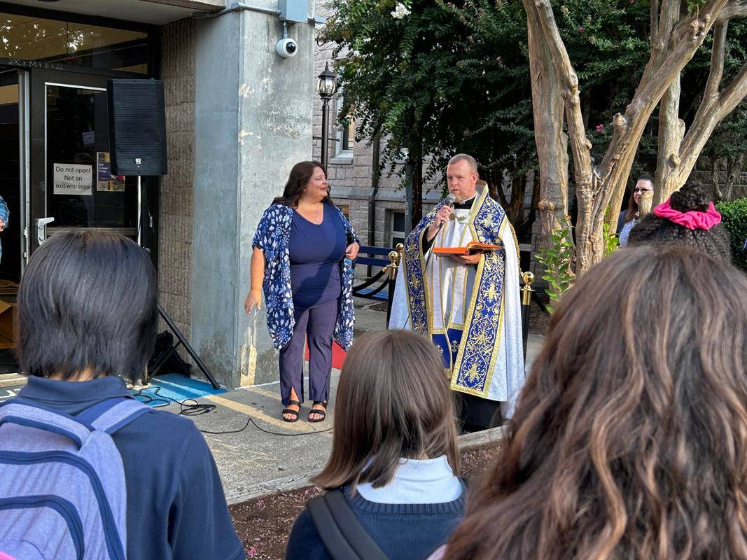 Father Casey Coleman blesses students as the return to Our Lady of Grace School in Greensboro.