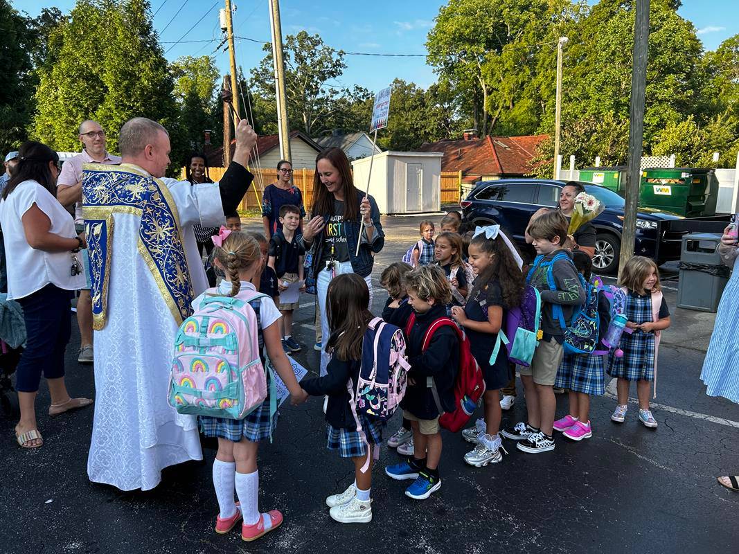 Father Casey Coleman blesses students as the return to Our Lady of Grace School in Greensboro.