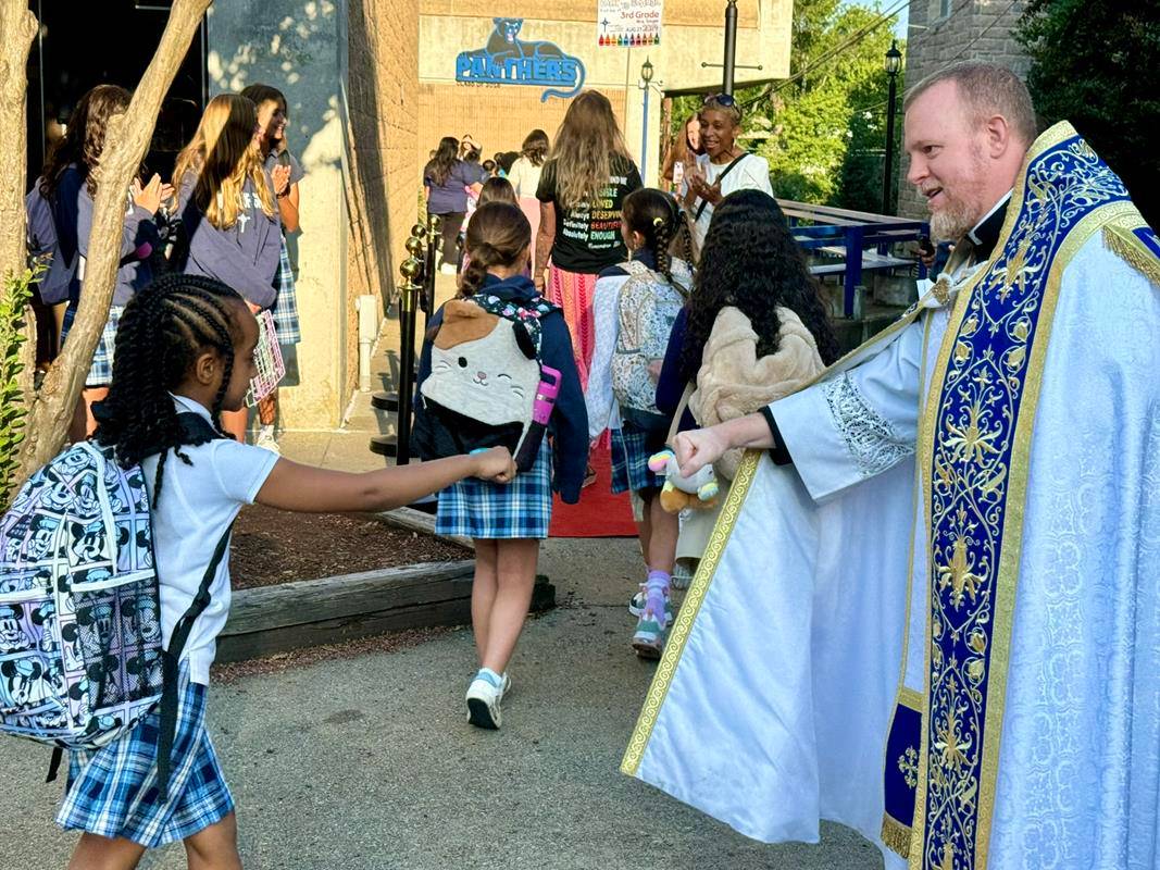 Father Casey Coleman blesses students as the return to Our Lady of Grace School in Greensboro.