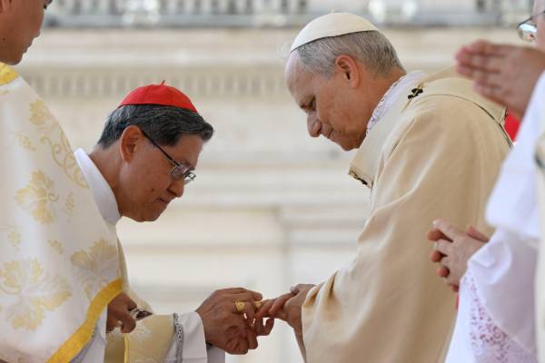Pope Leo XIV, left, receives the fisherman's ring, symbolizing his role as successor to St. Peter, from Filipino Cardinal Luis Antonio Tagle, right, during the pope's installation Mass in St. Peter's Square May 18. (CNS/Vatican Media)