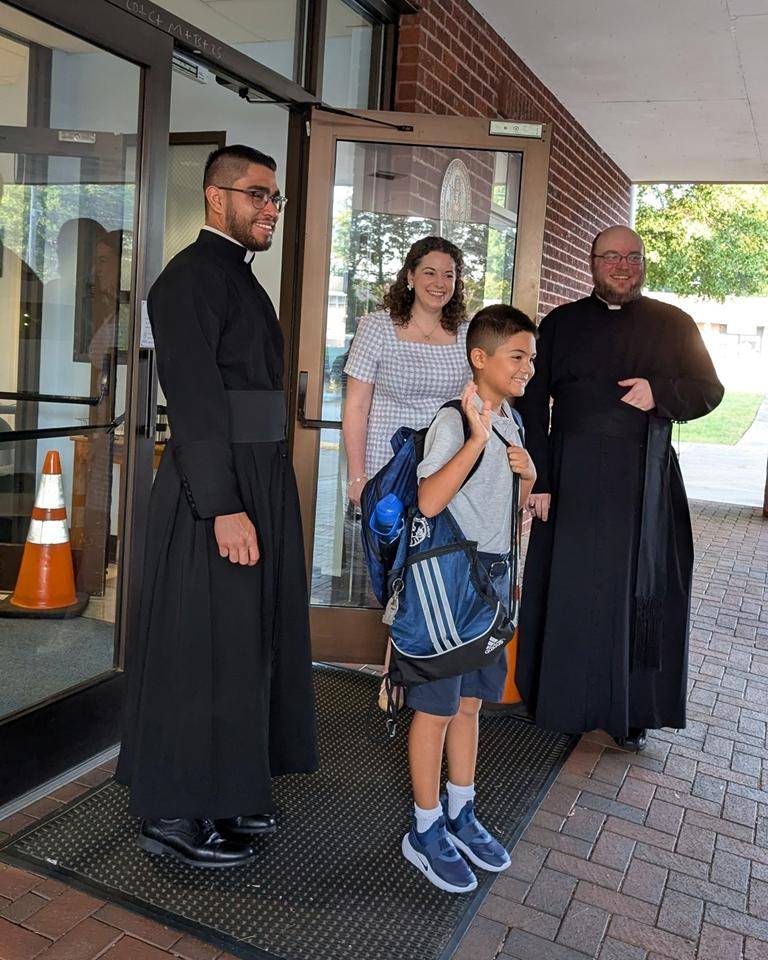 Father Cory Catron and Father José Palma welcome students to Our Lady of Mercy School in Winston-Salem. 